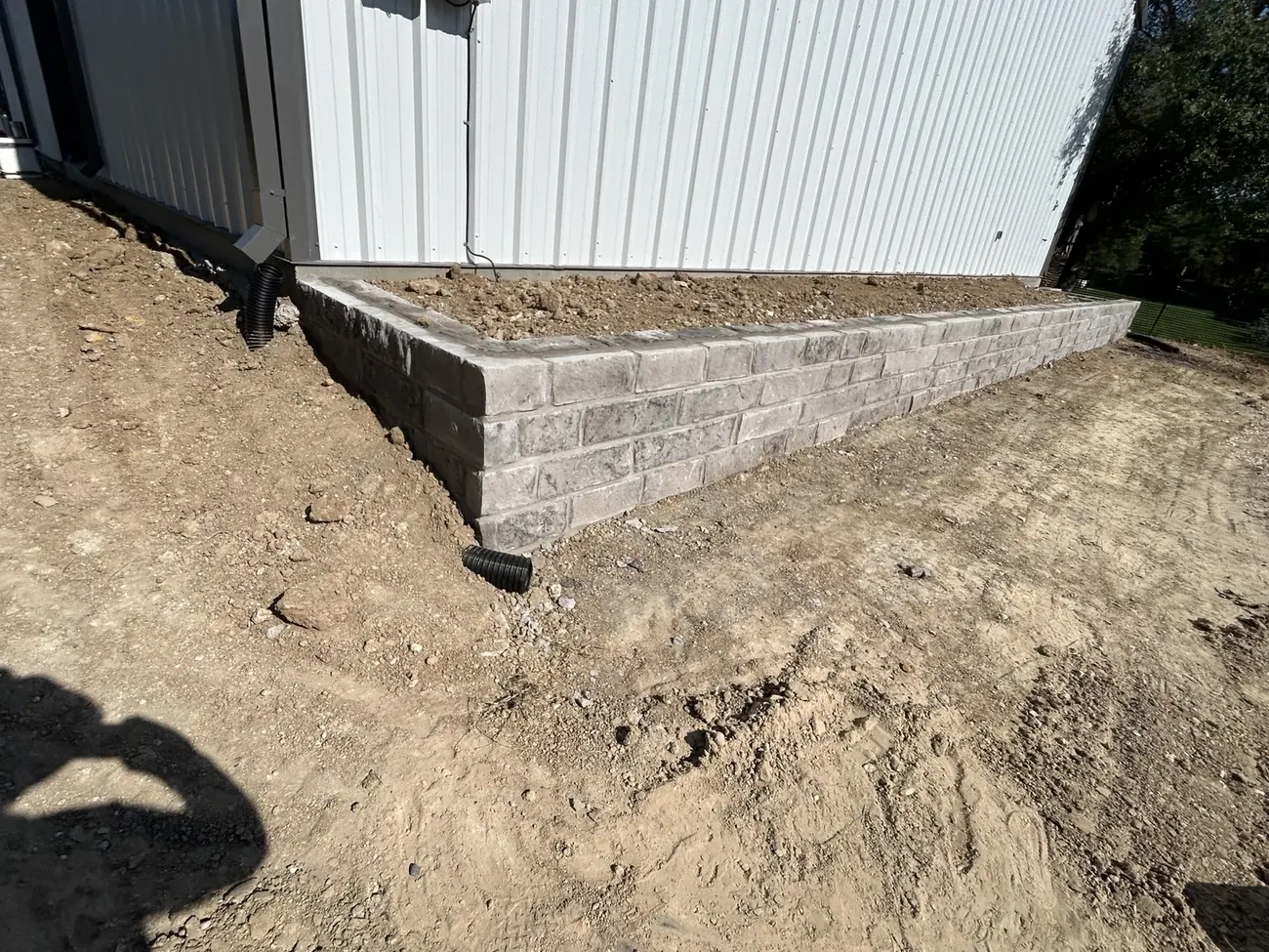 Gray masonry retaining wall beside metal building