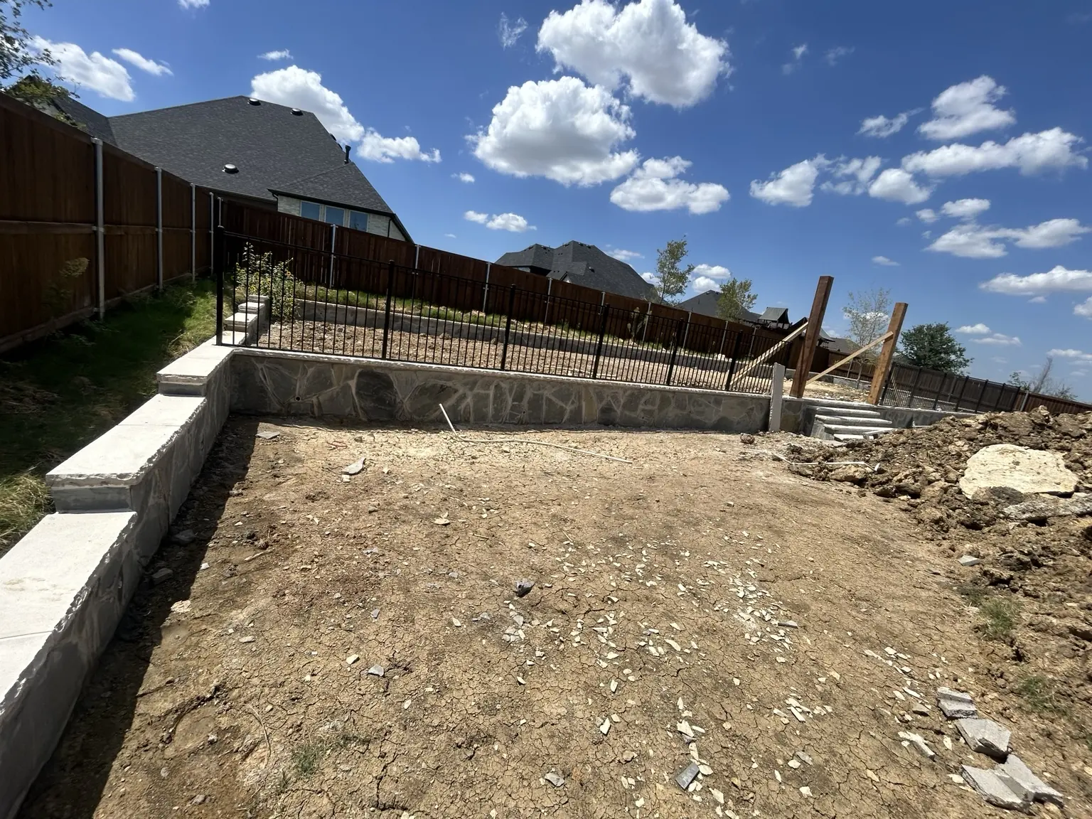 Finished retaining wall with stone veneer and black metal railing